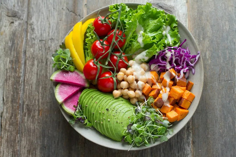 A rainbow veggie bowl with avocado, chickpeas, sweet potato, cherry tomatoes and red cabbage